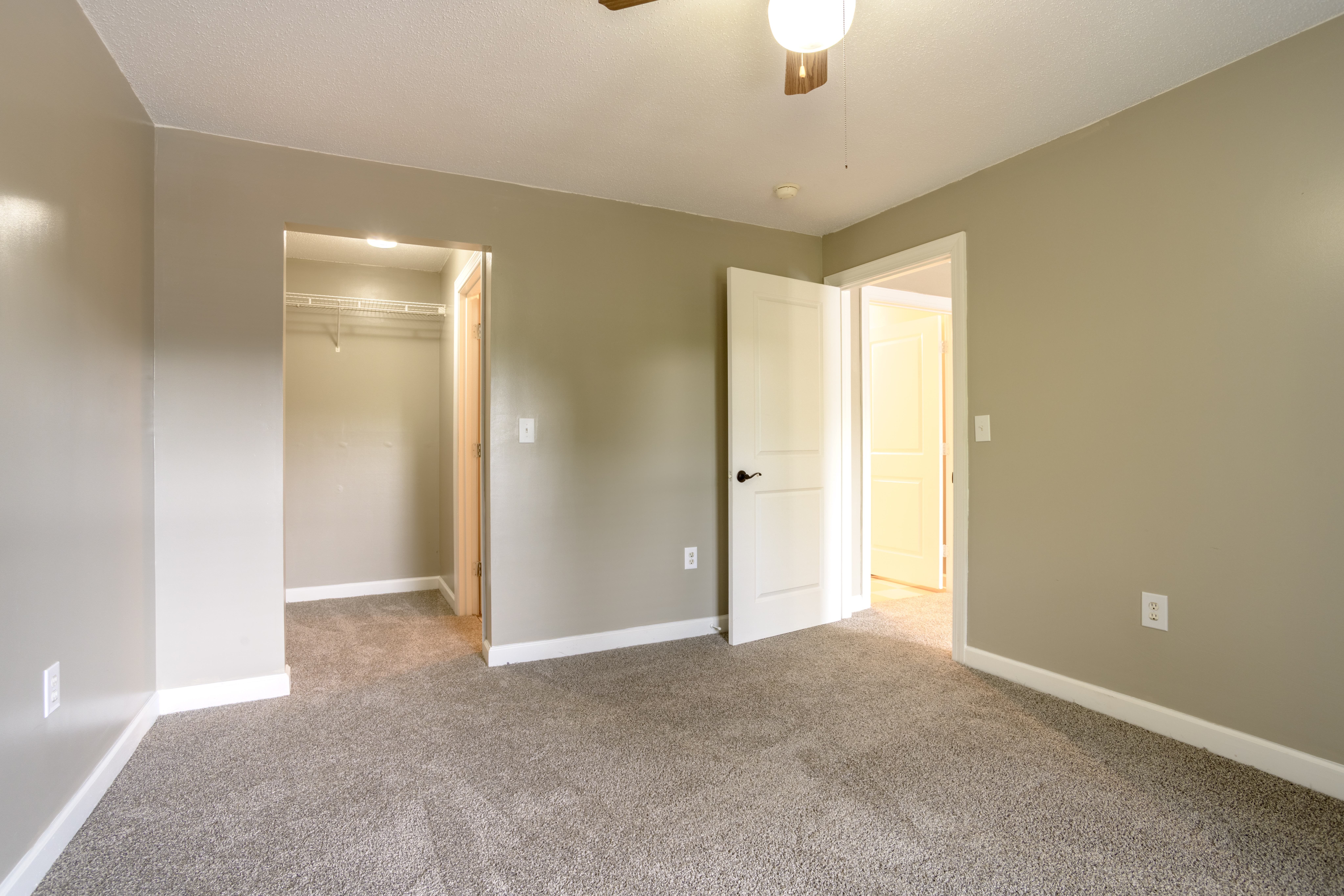 A room with a carpeted floor and a ceiling fan.,A room with a carpeted floor and a ceiling fan.